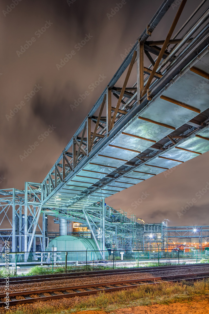 Obraz premium Night scene with pipeline overpass at petrochemical production plant, port of Antwerp, Belgium.