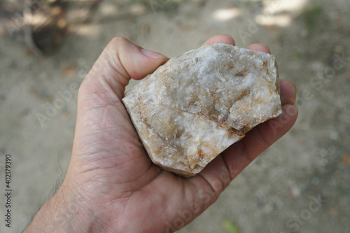 Raw quartzite rock stone in a hand. Quartzite is a nonfoliated metamorphic rock composed almost entirely of quartz.