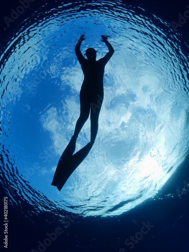 free diver silhouette underwater with sun and clous in the sky ocean scenery