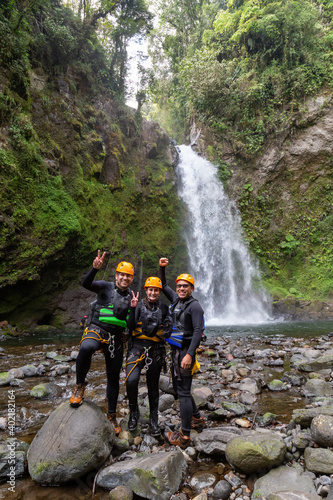 A group of young happy rock climbers in helmets and climbing equipment preparing for an adventure