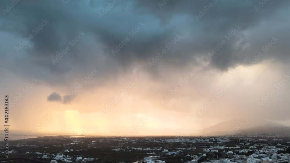 Aerial tilt down shot of stormy clouds rolling over Thera town in Santorini at sunset Aerial tilt down shot of stormy clouds rolling over Thera town in Santorini at sunset