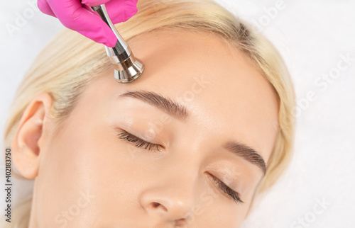Cosmetologist makes  procedure microdermabrasion on the face against acne and blackheads near the eyes. Women s cosmetology in the beauty salon.