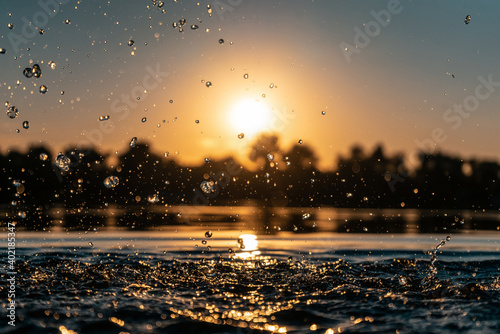 Fototapeta Naklejka Na Ścianę i Meble -  closeup of girl hand silhouette play or splash water in lake on beach at sunset