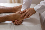 Close em mãos de massoterapeuta aplicando massagem em pé de paciente.