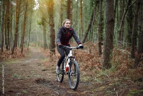 beautiful young woman mountain biking in the forest in winter
