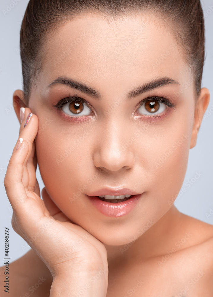 Portrait of a beautiful smiling brunette woman with healthy clean skin and fresh make-up. Aesthetic cosmetology and makeup concept.