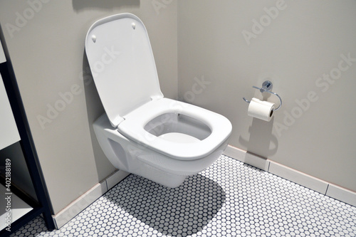 White toilet and toilet paper in a white-tiled luxury hotel bathroom photo