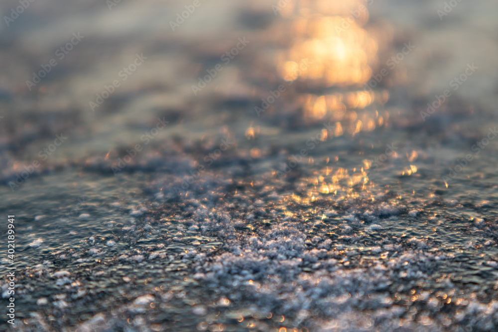 Frozen ice cold deep lake surface covered with snow close-up sparkling in orange sunset light. Blurred background Frozen ice cold deep lake surface covered with snow close-up sparkling in orange sunset light. Blurred background