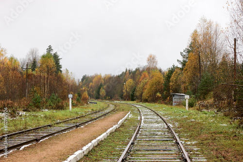 old abandoned station on railroad in autumn forest powdered by first snow