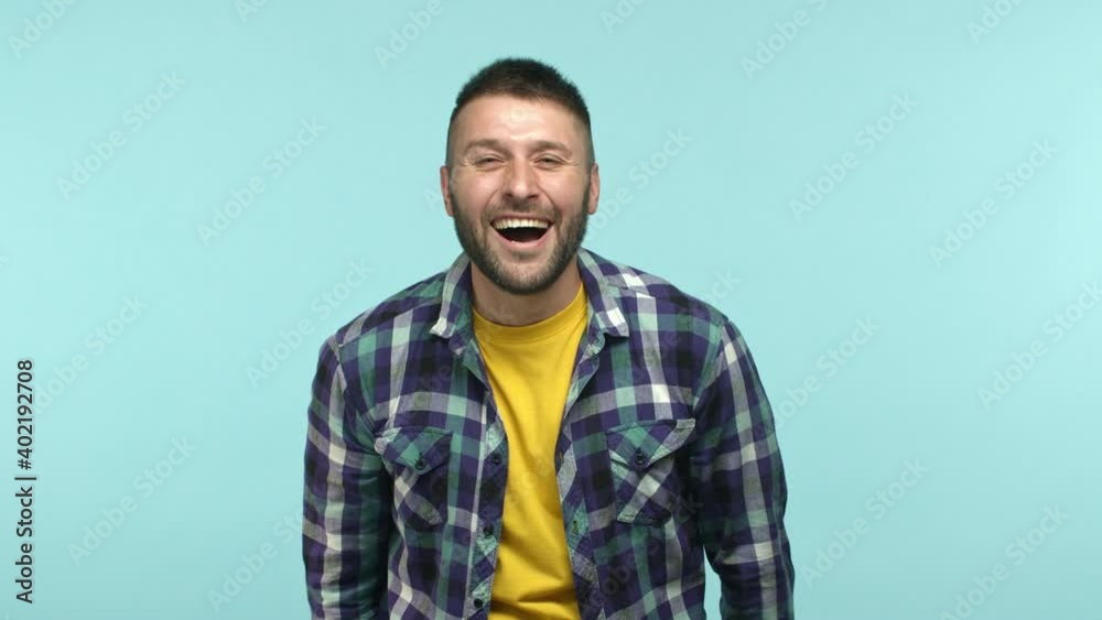 Slow motion of middle-aged guy having fun, pointing finger at camera see something funny, laughing out loud, chuckle and stand over blue background Slow motion of middle-aged guy having fun, pointing finger at camera see something funny, laughing out loud, chuckle and stand over blue background