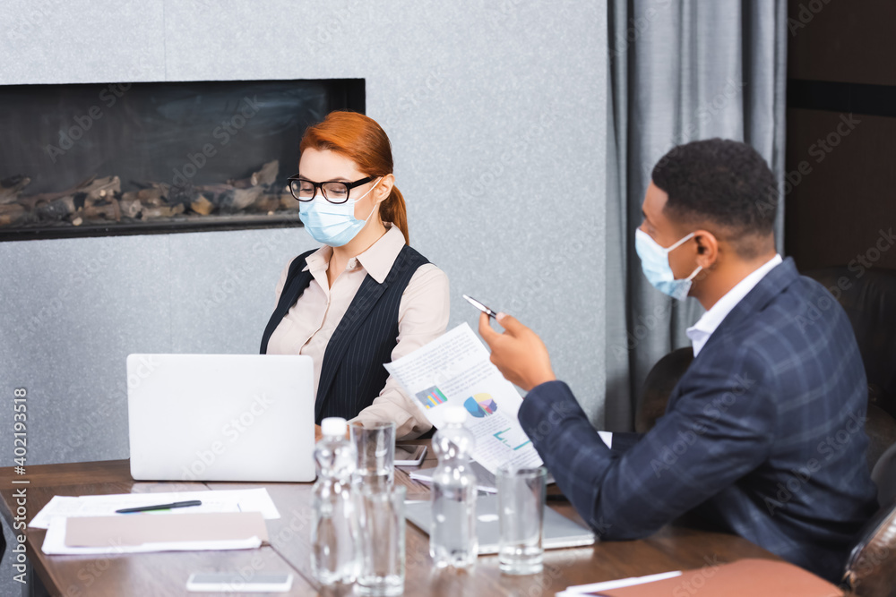 African american businessman with document pointing with pen while sitting near businesswoman at workplace. African american businessman with document pointing with pen while sitting near businesswoman at workplace.