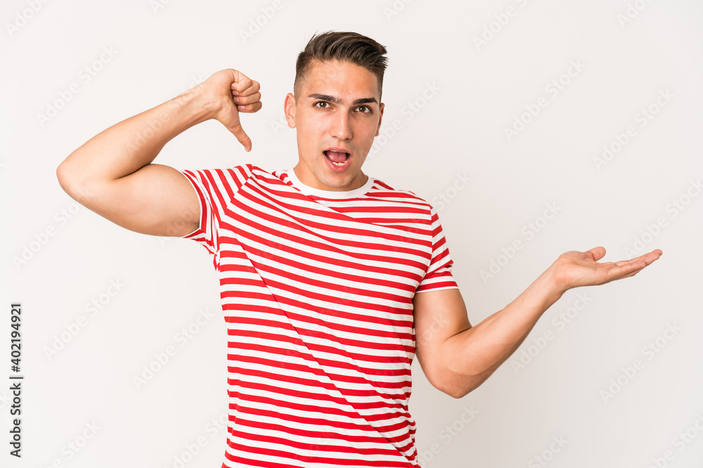 Young caucasian handsome man isolated holds copy space on a palm, keep hand over cheek. Amazed and delighted. Young caucasian handsome man isolated holds copy space on a palm, keep hand over cheek. Amazed and delighted.