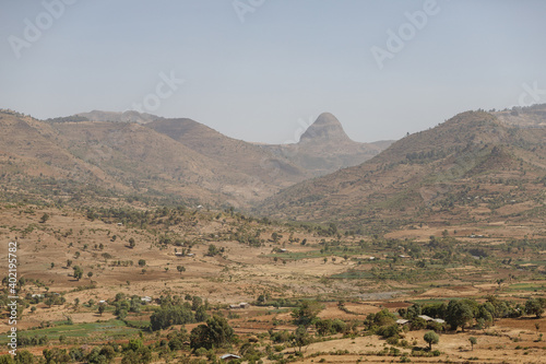 Ethiopia mountain valley landscape with some trees and all yellow-dried grass in dry weather