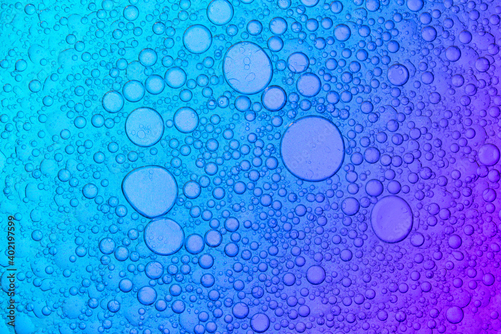 Mixture of oil and water on blue and purple Background, macro shot
