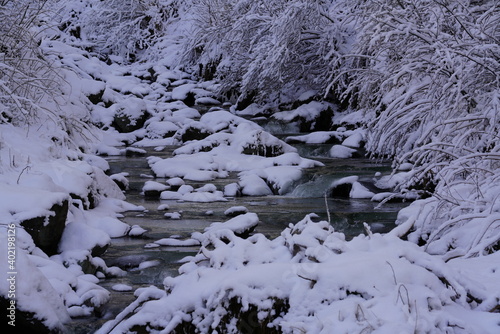 a small creek with snow on the stones in winter 