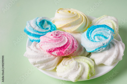 Homemade sweet colored meringue on green background. .Dessert.