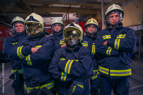 Portrait of group firefighters in front of firetruck inside the fire station © qunica.com