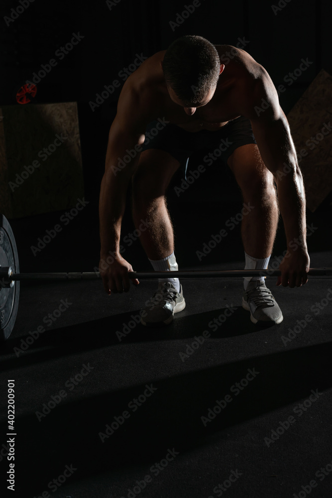 Close up silhouette of a bodybuilder doing barbel overhead shoulder press in a gym while flexing his muscles portrait. Close up silhouette of a bodybuilder doing barbel overhead shoulder press in a gym while flexing his muscles portrait.