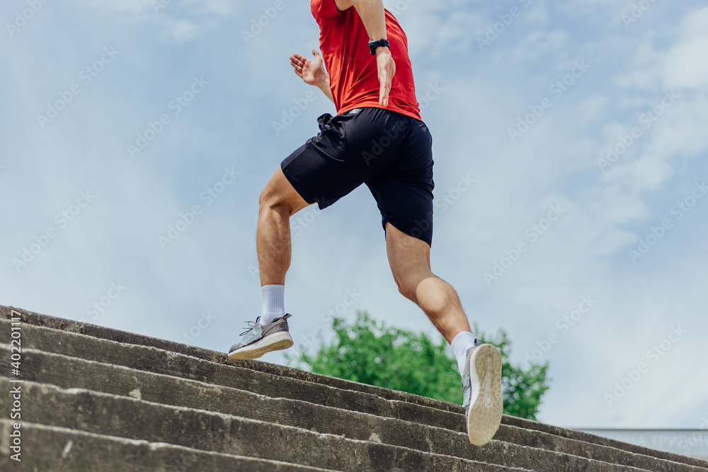 Fit male athlete performing stairs workout, running up climbing stairs