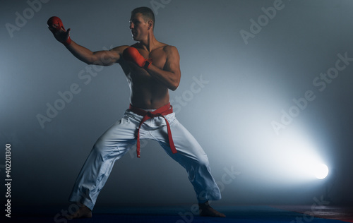 Professional karate fighter kicking. Isolated on a dark background