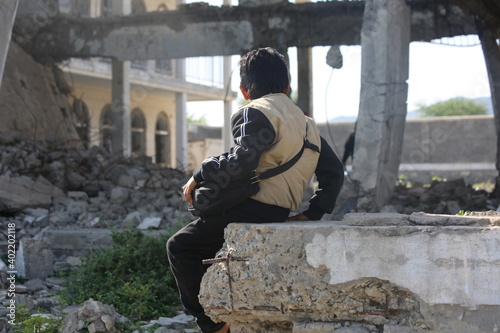 A sad Yemeni child sits on the rubble of his school, destroyed by the war in Yemen