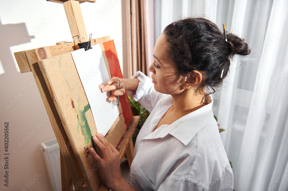 Side view of a female artist performing shading of a pencil drawing ...