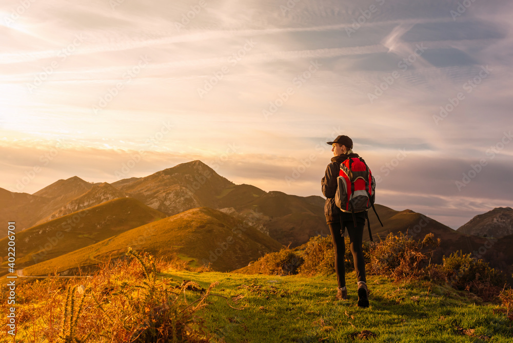 Traveler woman with backpack doing a mountain route and watching a beautiful sunset. hiking and mountain.