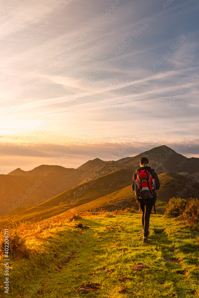 Traveler woman with backpack doing a mountain route and watching a beautiful sunset. hiking and mountain.