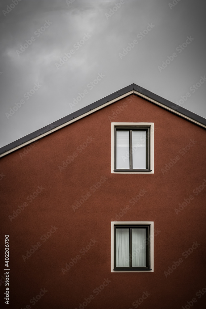 Red house against dark cloudy sky