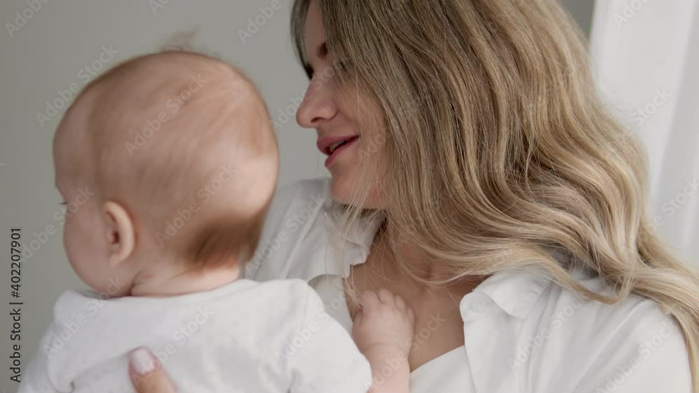Beautiful mommy kissing her pretty tender baby, enjoying smell of little child Beautiful mommy kissing her pretty tender baby, enjoying smell of little child