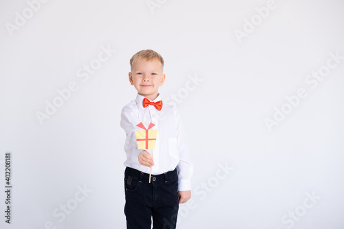 boy in suit and red bow tie holds the toppers or stikcers gift design on a white background.