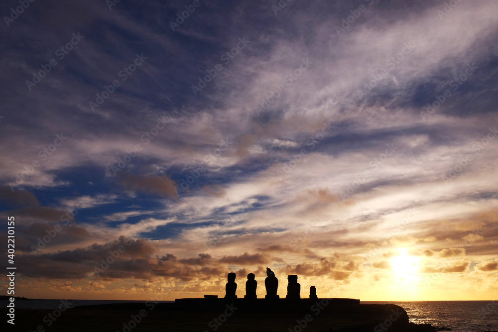 Moai statues at the Ahu Tahai Ceremonial complex on Easter Island, against a colorful sunset sky.