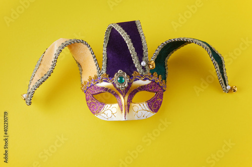Mardi gras face mask on yellow background with copy space.