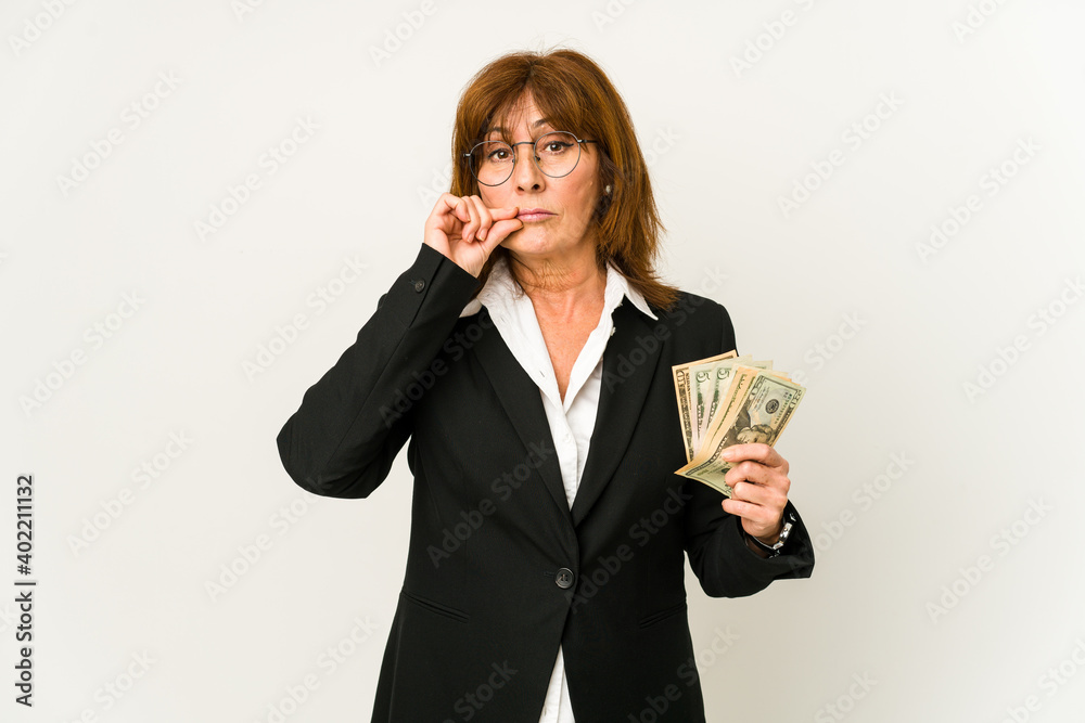 Middle age caucasian business woman holding banknotes isolated with fingers on lips keeping a secret. Middle age caucasian business woman holding banknotes isolated with fingers on lips keeping a secret.