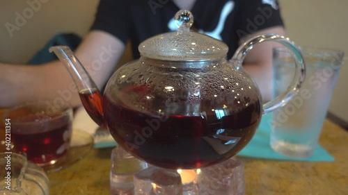 Warming up Glass Teapot with Removable Infuser with herbal black tea on the table. 