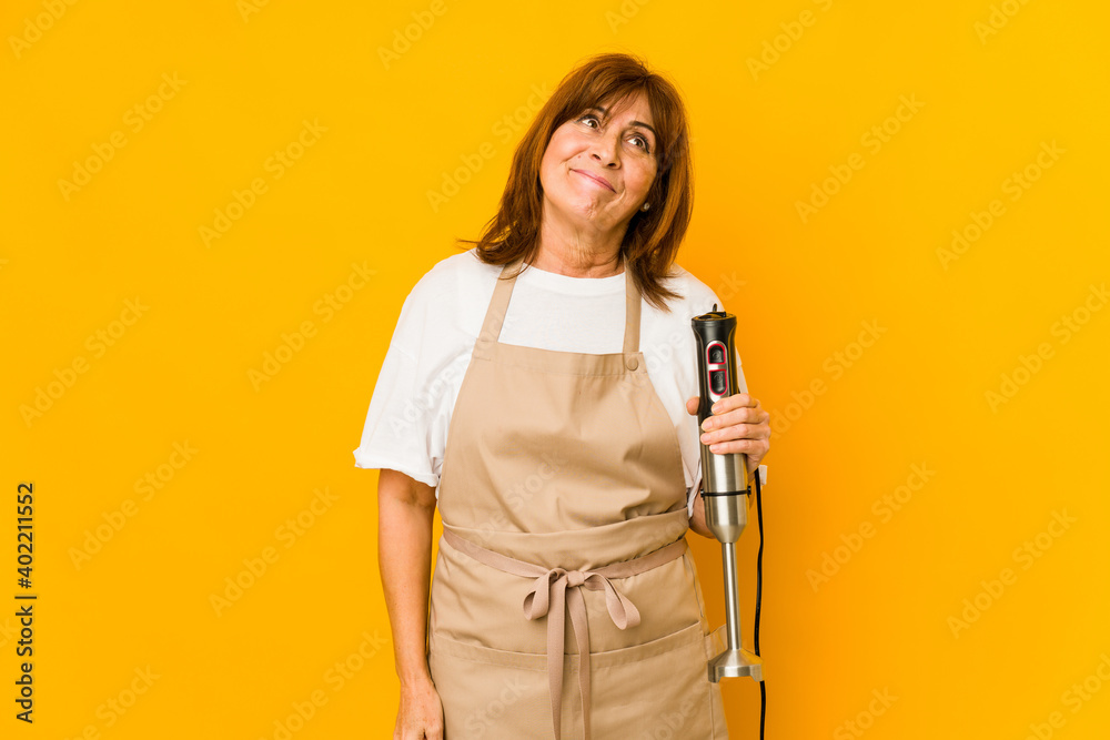 Middle age caucasian cook woman holding a mixer isolated dreaming of achieving goals and purposes