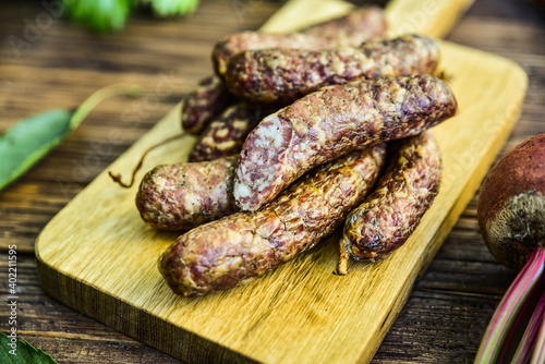 Sausage served on an oak board among vegetables from the home garden.