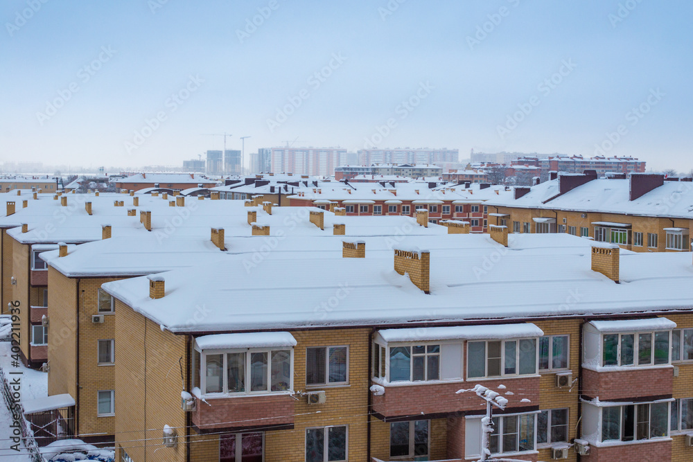 Snow-covered roofs of houses in winter. City panorama, top view