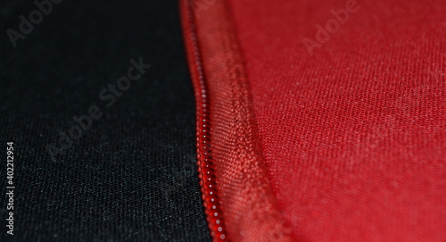 close-up view of a zipper sewn to red and black neoprene fabrics