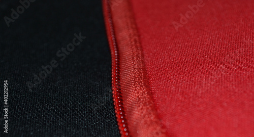 close-up view of a zipper sewn to red and black neoprene fabrics