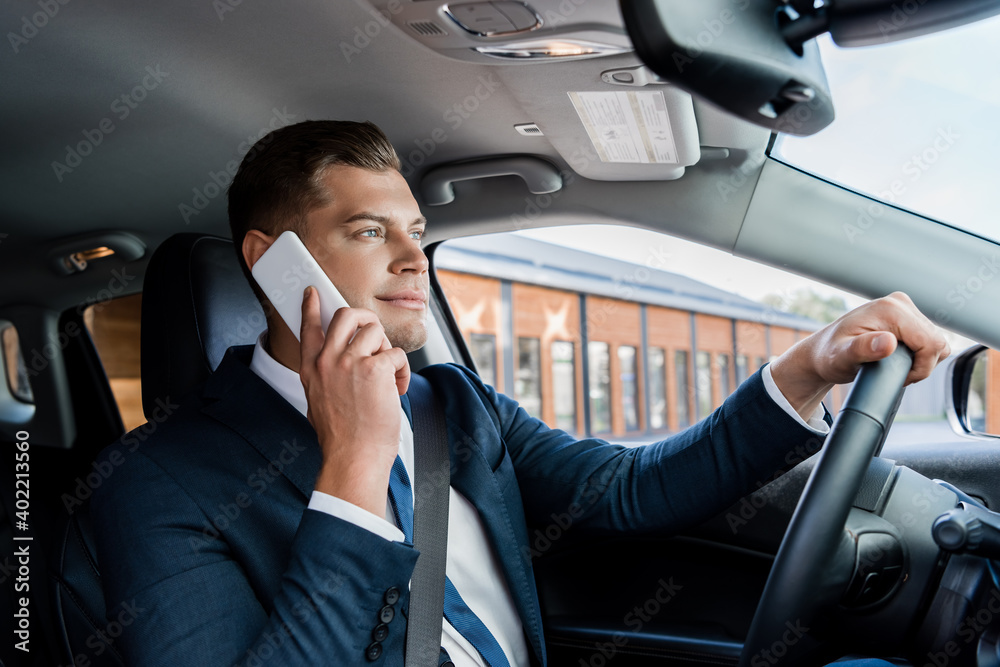 Businessman talking on mobile phone while driving car.