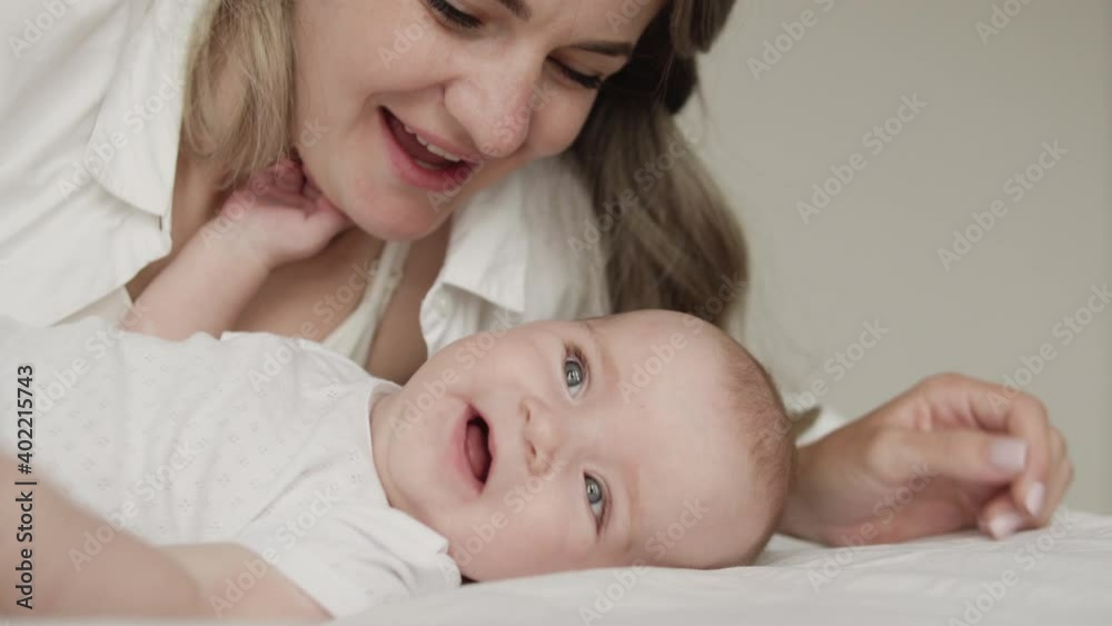 Cheerful mom kissing cute infant, admiring newborn, unconditional parental love Cheerful mom kissing cute infant, admiring newborn, unconditional parental love