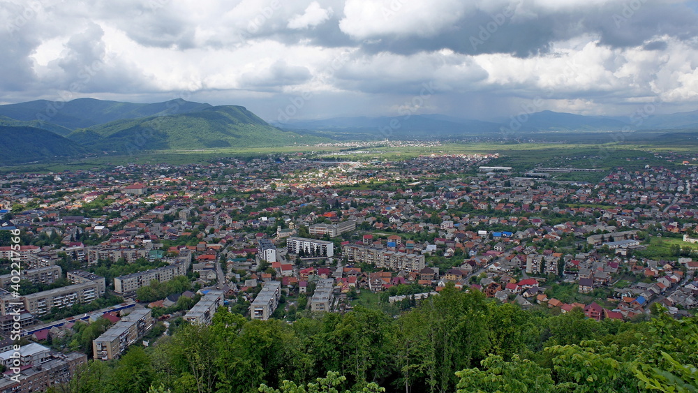 KHUST, UKRAINE - MAY 11, 2019. panoramic city view. view from the castle mountain and dark clouds before the storm and mountains behind on the background
