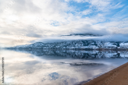 Snow covered mountain  fog  clouds  and sunlight reflected in calm lake