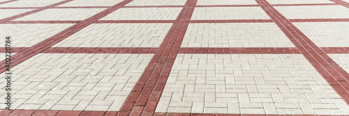 Stone pavement. Texture of stone paved ground. Brown paving slabs on a pedestrian sidewalk or road. Perspective. Wide panoramic texture for background and design.