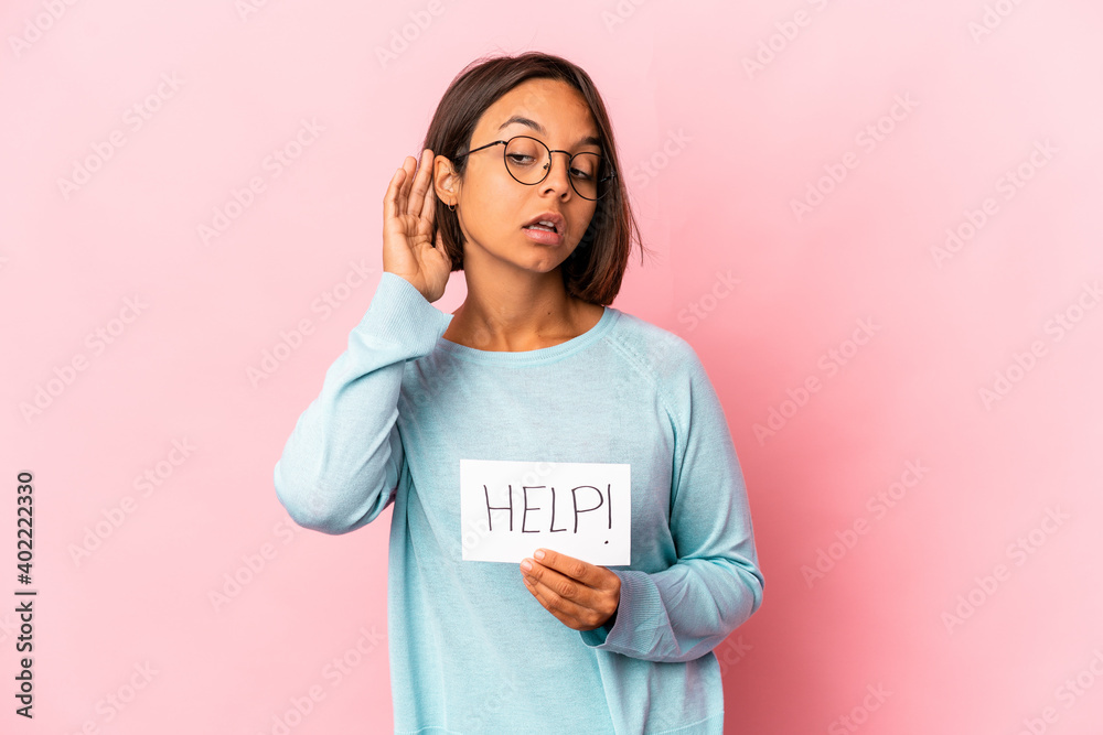 Young hispanic mixed race woman holding a help poster trying to listening a gossip. Young hispanic mixed race woman holding a help poster trying to listening a gossip.