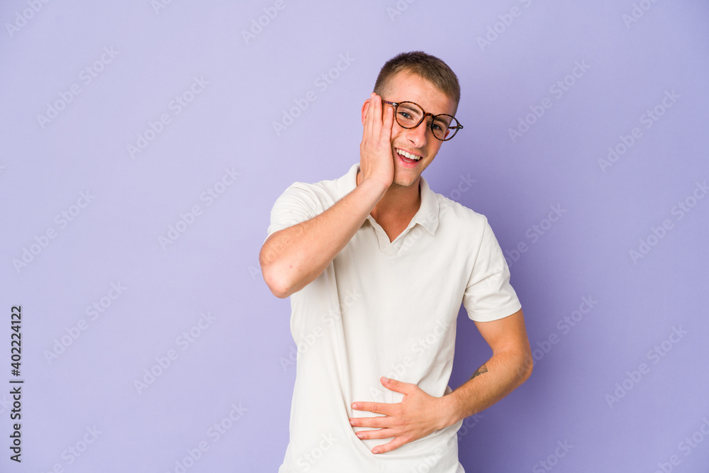 Young caucasian handsome man laughs happily and has fun keeping hands on stomach. Young caucasian handsome man laughs happily and has fun keeping hands on stomach.