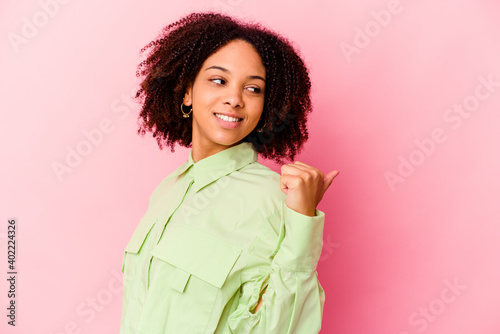 Young african american mixed race woman isolated points with thumb finger away, laughing and carefree.