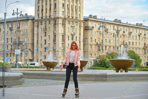 Girl skating on roller skates on the background of high-rise Stalin's building and fountains in St. Petersburg