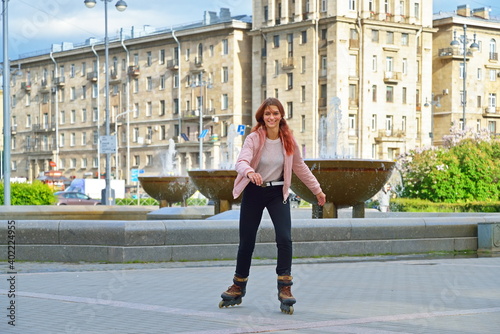 Girl skating on roller skates on the background of fountains and high-rise Stalin's building in St. Petersburg